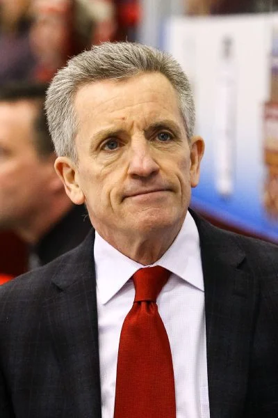 A man in a suit and tie looking to his left.