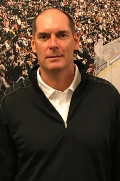 A man in black jacket standing next to crowd.