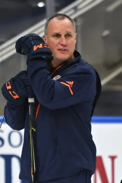 A man holding a hockey stick on top of a rink.