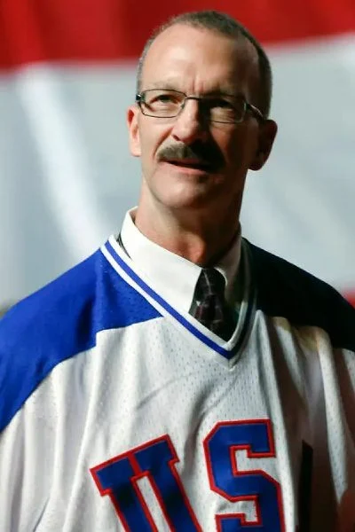 A man with glasses and a mustache wearing a baseball uniform.