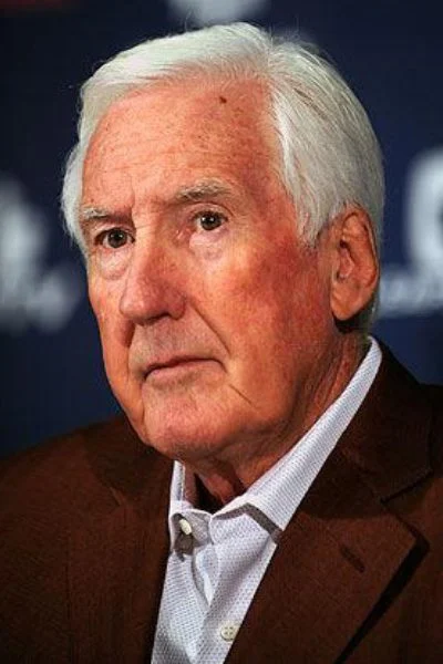 A man with white hair and wearing a suit.