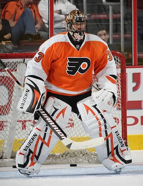 A goalie in an orange and white uniform.