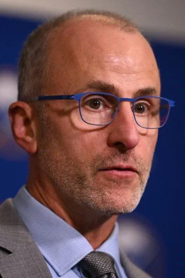 A man with glasses and a beard is looking at the camera.