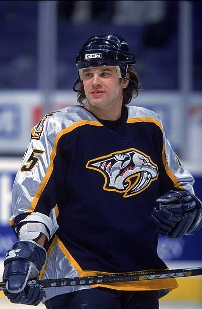 A man in hockey uniform with gloves on.