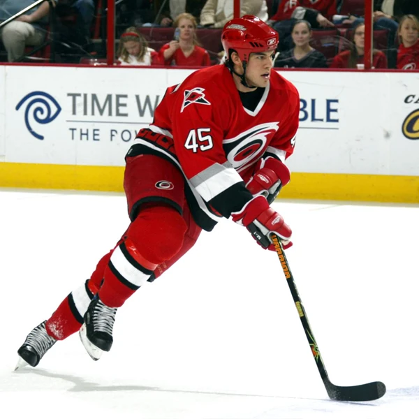 A hockey player in red and black is playing ice hockey.