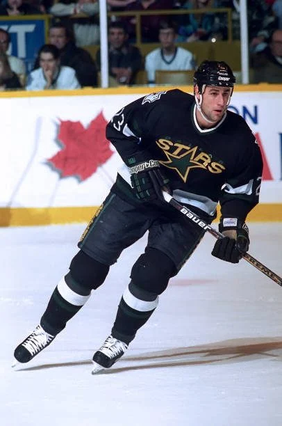 A hockey player in black uniform holding a stick.
