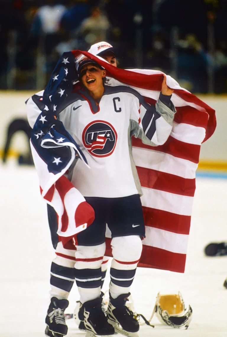 A man holding an american flag on top of the ice.