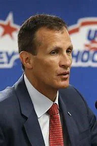 A man in suit and tie speaking at a podium.