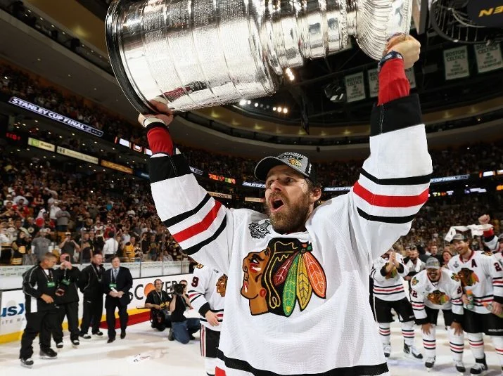 A man holding up the stanley cup in front of an audience.