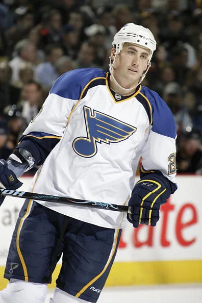 A hockey player in white and blue uniform holding a stick.
