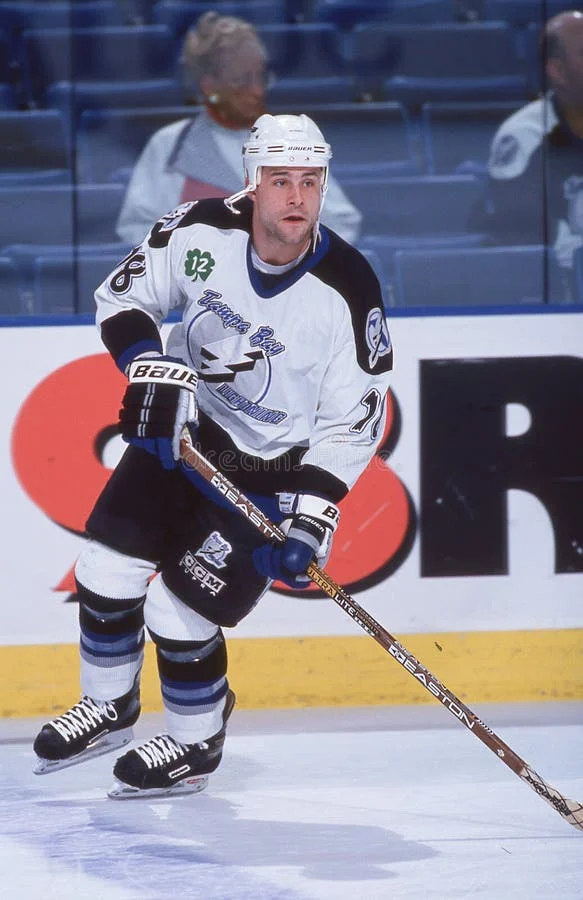 A hockey player is holding his stick while standing on the ice.