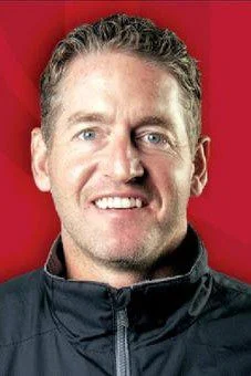 A man with a black jacket smiling for the camera.