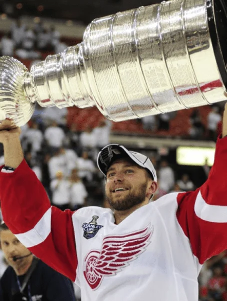 A man holding up the cup in front of fans.