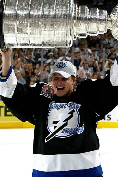 A man holding up the stanley cup in front of a crowd.