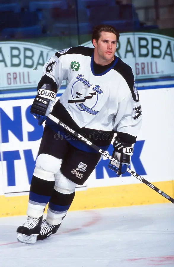 A hockey player in white and black uniform.